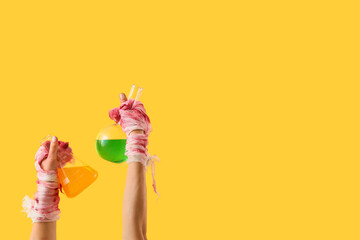 Mummy hands holding flasks with potions on yellow background. Halloween celebration