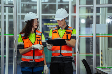 Two people wearing safety vests and gloves. Team of diverse engineers having a discussion and...