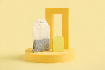 Composition with tea bag and plaster podiums on yellow background, closeup