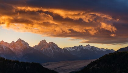 Fototapeta premium majestic cloudscape over mountain range illuminated by golden dawn light