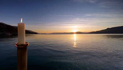 a beautifully detailed candle burns gently on a surface near calm water as dusk approaches the soft light creates a peaceful ambiance inviting moments of introspection