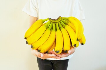 白背景に室内で子供に抱えられた大きなバナナの一房