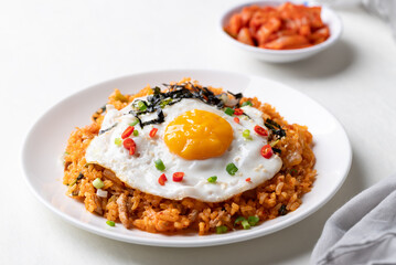 Korean kimchi fried rice with fried egg, pork, sesame seed, chili, spring onion and seaweed on plate and kimchi cabbage on white background