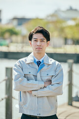 腕を組んで立つ作業服姿の男性