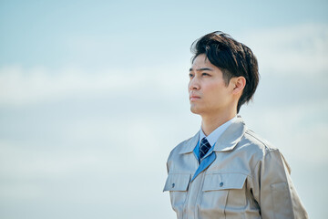 屋外で未来を見つめる作業服姿の男性