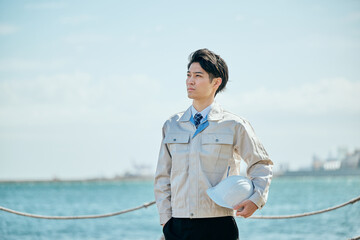 屋外で未来を見つめる作業服姿の男性