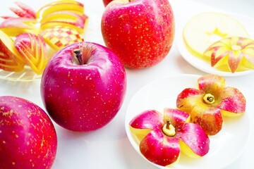 白背景にシンプルな花の形に飾り切りされた林檎と色々な飾り切りをしたリンゴ