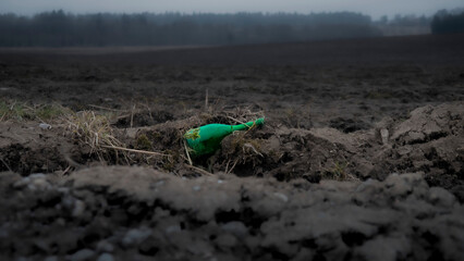 bottle in nature; discarded bottle on a field
