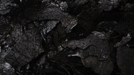 Dark textured black coal background with rough surface details, perfect for use in design, food styling, or artistic projects. Close up, top view