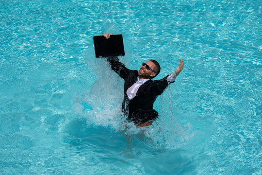 Crazy business. Fun business lifestyle. Handsome excited business man in suit jump with laptop in swimming pool. Funny businessman. Freelance concept, summer travel. Business success.