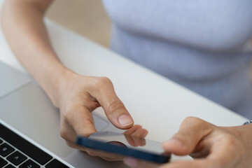 Woman using mobile smartphone, finger touching on screen with laptop computer and digital tablet on...