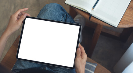 Mockup image of woman using digital tablet with blank white screen during working at coffee shop,...