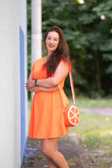Portrait of a beautiful young plump girl in an orange dress in the forest.