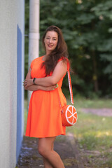 Portrait of a beautiful young plump girl in an orange dress in the forest.