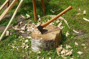 Axe Stuck in a Wooden Log Outdoors. Axe and Shavings on a Tree Stump. Traditional Woodworking Scene.