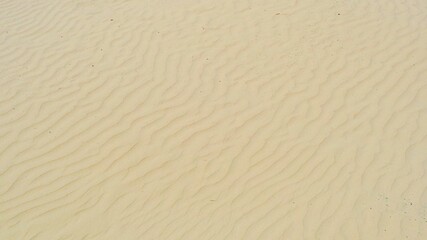 Close-up view of sand texture with natural wind-formed ripples, creating a minimalistic and...