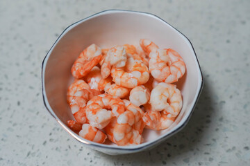 A large pile of boiled frozen shrimp on a white plate.