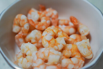 A large pile of boiled frozen shrimp on a white plate.