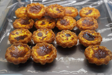 Stack of Portuguese egg tart (Pasteis de Nata) display in front of shop, A delicious local favourite dessert with pastry shell, Sweet tarts with an aromatic custard that gets baked and scorched on top