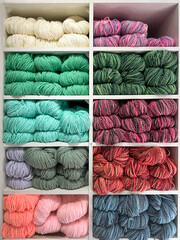 vibrant assortment of wool, wool blend, and cotton yarns in various colors neatly arranged on clean...