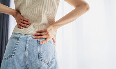 Woman standing holding her lower back suffering from chronic back pain. Healthcare and medical...