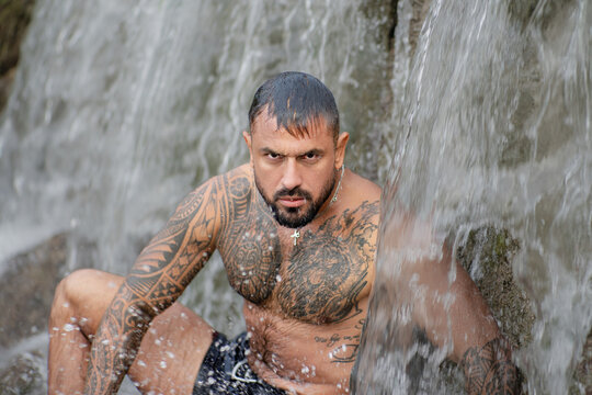 Sexy male body. Shirtless man splashing under waterfall. Fit and strong body. Handsome model enjoying summer water. Athletic male body. Man beauty on nature. Muscular body with water drops.