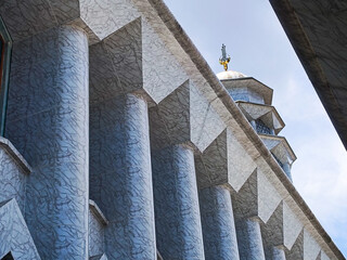Modern mosque architecture with tall blue columns and a towering minaret shot from below. Islamic...