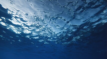 Dark Blue Ocean Surface Seen from Underwater – Sunbeams Piercing Deep Waters, Waves Rippling Above in Indigo Hues