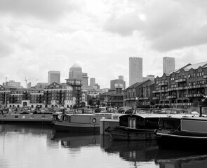 Canary wharf reflecting on the calm waters of limehouse basin, london, uk