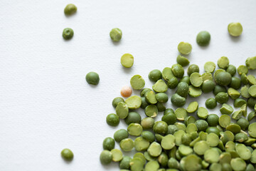 dried bright green split peas on white background in the corner closeup