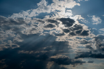 Sunlight streaming through dramatic clouds in blue sky, natural sun rays creating spiritual and atmospheric effect, ideal for weather, nature, hope or inspiration related visual themes