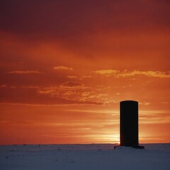 Dark Silhouette of a Gas Pillar Against a Bright Red and Orange Sunset Sky