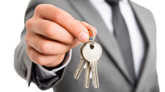Businessman holding keys in a suit for property transaction