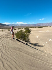 Two teens on a sand dune at Mesquite Flat Sand Dunes, Death Valley, USA; one sliding down and one...