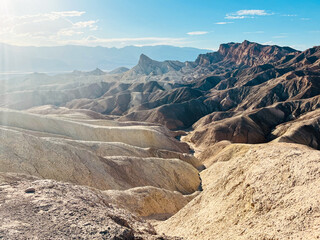 Sunset over the layered badlands at Zabriskie Point in Death Valley National Park with warm golden light and dramatic shadows, no people in the scene