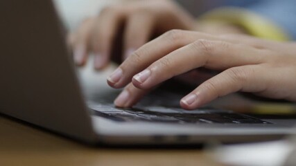 Close-up of young Asian woman's hands, early 20s, typing on laptop in library setting. Represents digital work, education, productivity, and remote study or freelance concepts. - Powered by Adobe