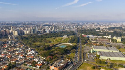 Wide aerial view of Curitiba showing Botanical Garden, residential areas, and main road under clear sky.