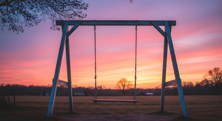 Fototapeta premium Wooden swing set at sunset with beautiful pink and orange sky in the background. Serene and calming view.