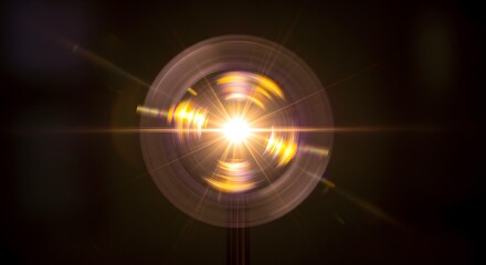 Fototapeta premium Circular light pattern with a bright central burst against a dark background with lens flare effects.