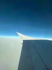 Plane wing against cloud and gradient night sky with a shadow cast on the wing. 
