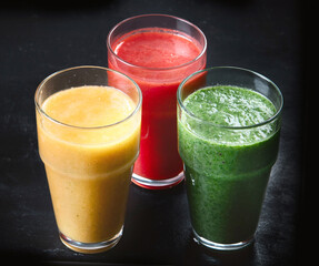 Different types of smoothies on black background.