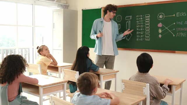 Caucasian teacher talking and explain about math theory at classroom while looking at student. Smart skilled instructor teaching and pointing at blackboard while standing in front of board. Pedagogy. - Powered by Adobe