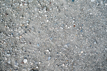 Close-up view of a gravel surface with small rocks and sand, creating a natural stone texture background for design or construction concepts.