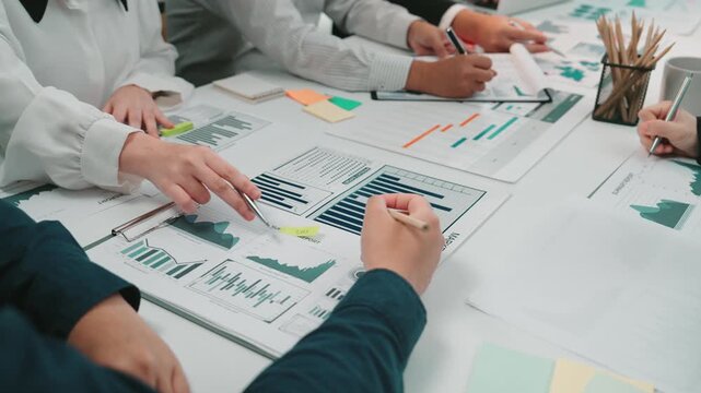 A diverse team of professionals collaborates in an office setting, analyzing charts and graphs on a table. They engage in strategic discussions to derive insights and drive business growth. SACTR