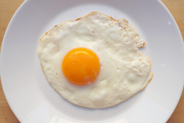 Fried egg on white dish close up