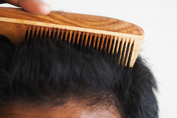 Man combing black hair with wooden comb for neat look