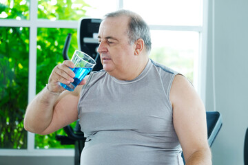 A man takes a break to drink water after exercising at the gym as part of his weight loss workout.