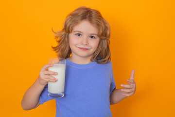 Kid drink fresh milk. Child with glass of milk, isolated on yellow studio background.