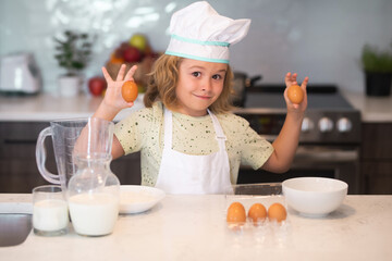 Kid chef cook with eggs at kitchen. Kid chef cook cookery at kitchen. Portrait of little child in uniform of cook. Cute child to be a chef. Child in chef hat.
