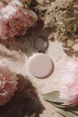 Round Smart Tracker Keychain Surrounded by Soft Flowers and Shadows